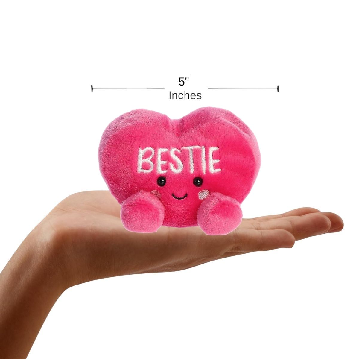 Sizing graphic showing the 5-inch Palm Pals Bestie Candy Heart plush sitting perfectly in the palm of a hand to demonstrate its small scale.