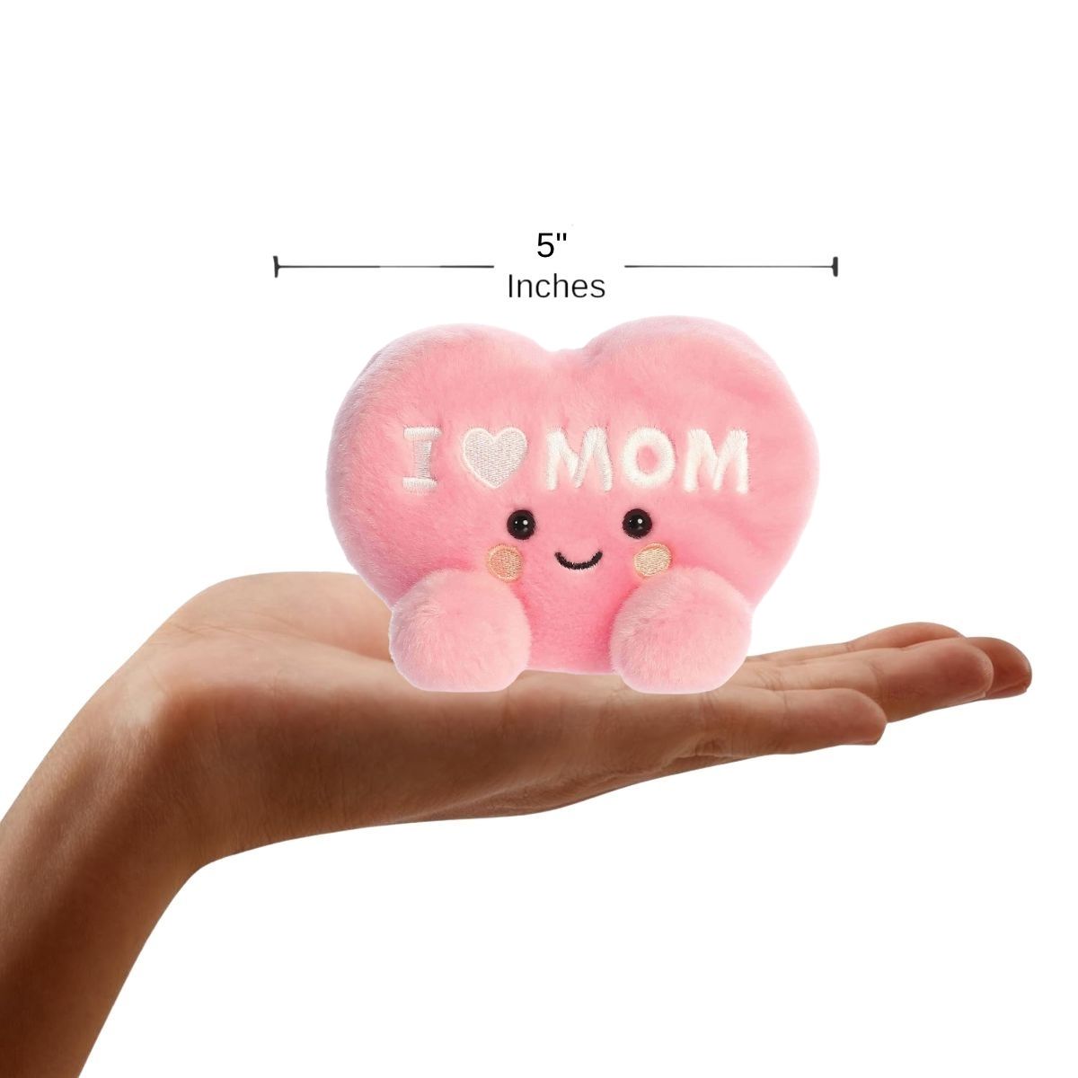 Aurora Palm Pals Pink heart-shaped plush toy with 'I ❤️ MOM' text held in a hand, with a measurement label indicating 5⅓ inches.