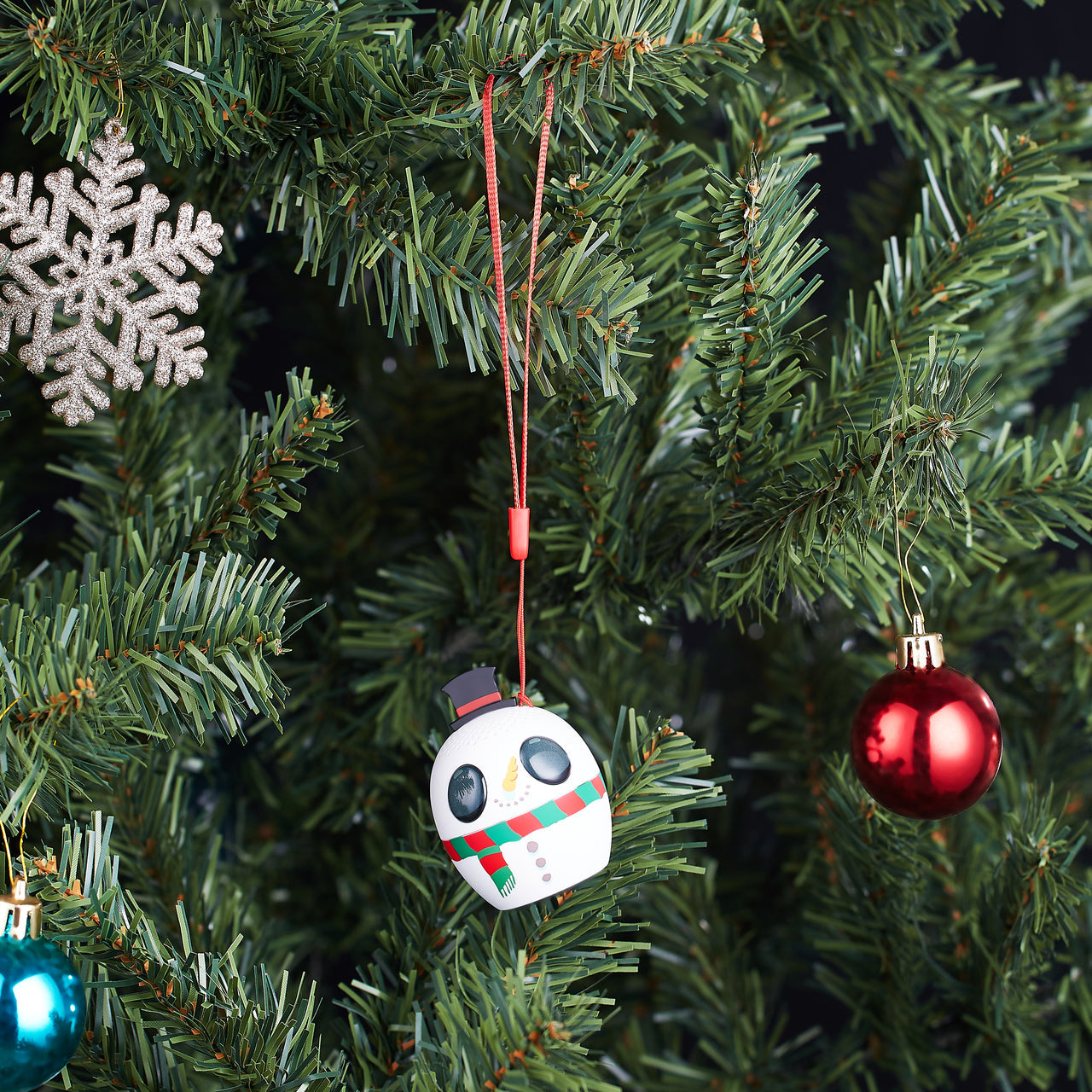 The Bitty Boomers Fortnite Snowman Bluetooth speaker hanging on a decorated Christmas tree like a festive holiday ornament.