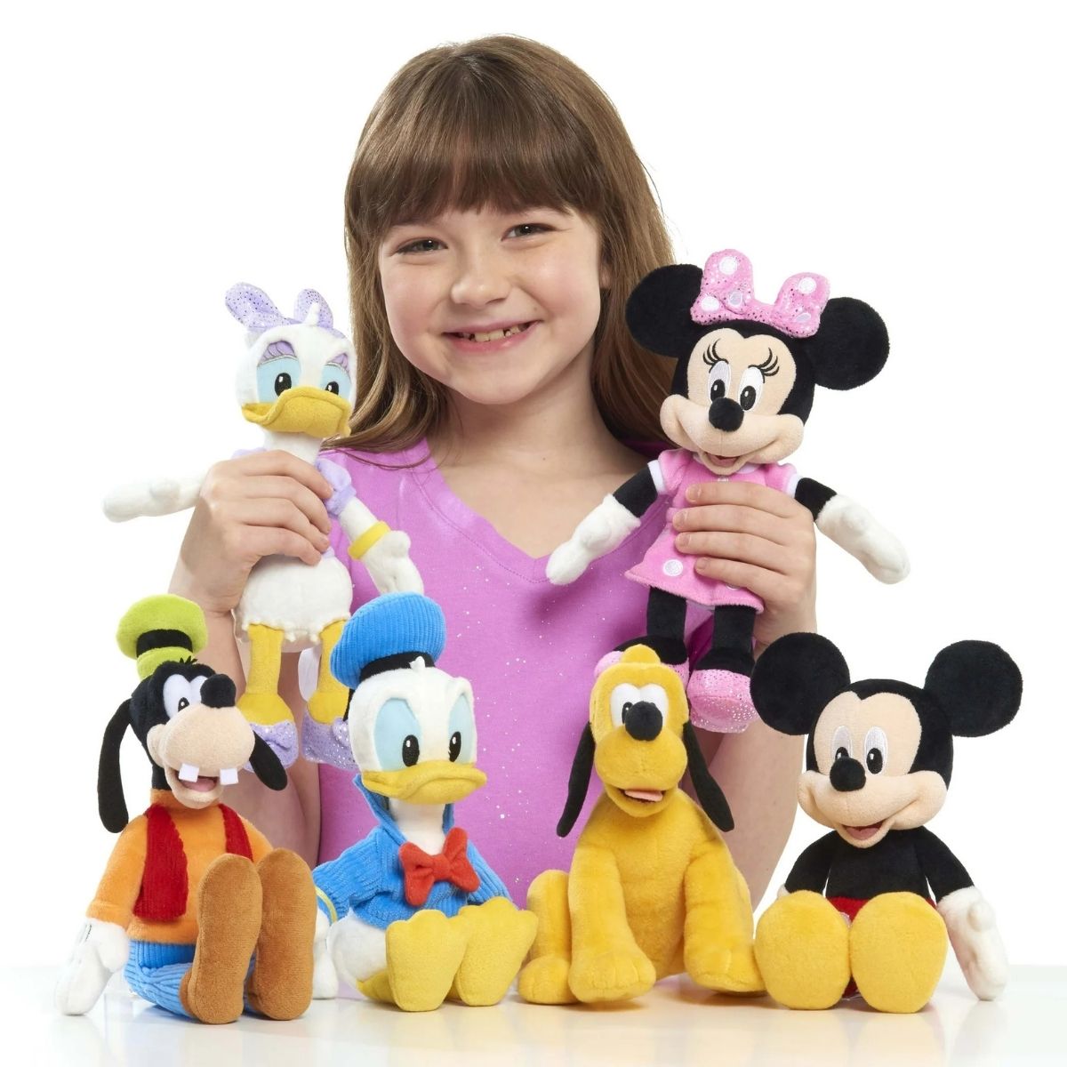 Young girl holding a collection of Disney Junior 9-inch bean plush toys including Minnie, Mickey, Donald, Daisy, Goofy, and Pluto.