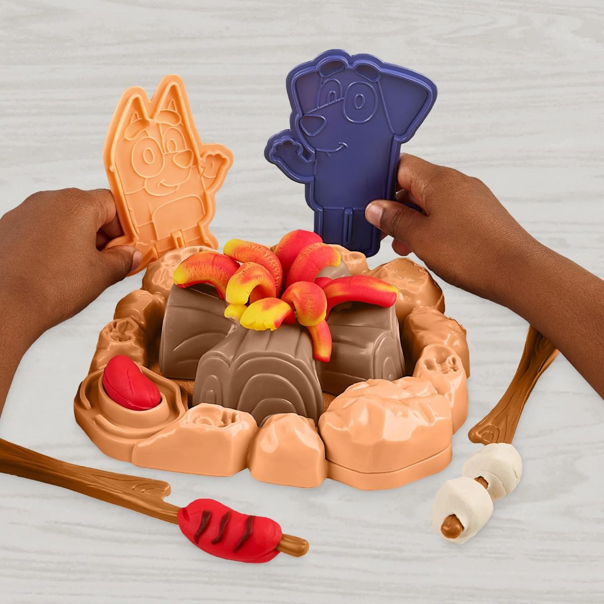 Hands-on play thumbnail showing kids roasting Play-Doh marshmallows on a stick next to standing Bluey and Jean-Luc figures.