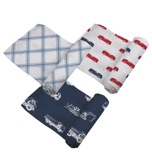 Top-down view of the three cotton muslin swaddle blankets partially unrolled, featuring construction, plaid, and fire truck prints.