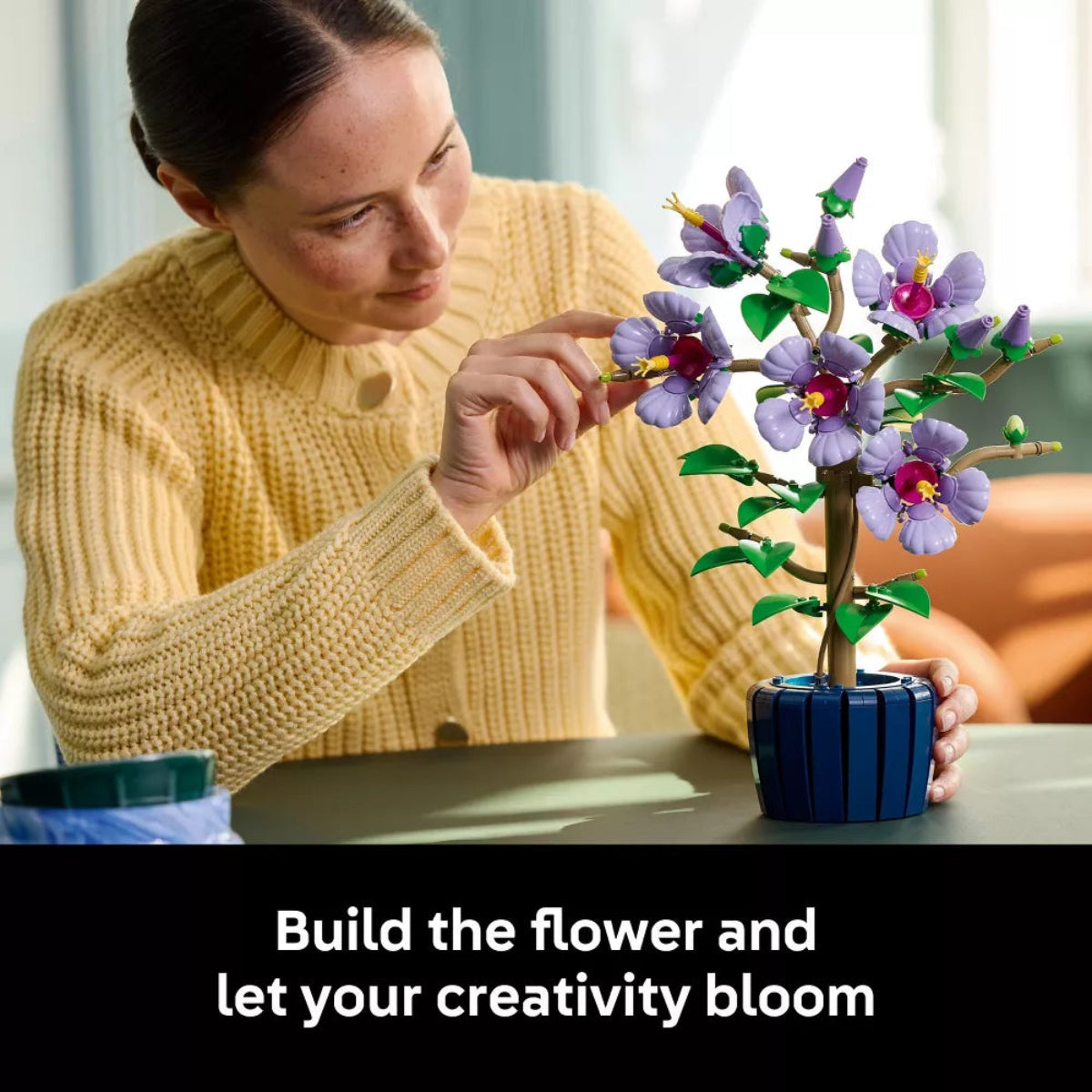 Woman assembling a colorful flower model with text 'Build the flower and let your creativity bloom'.