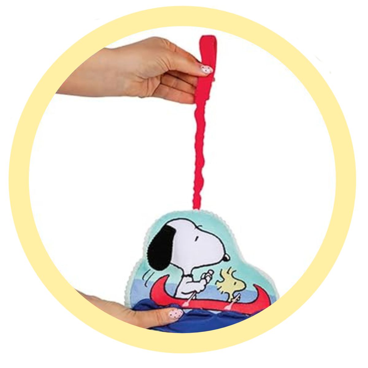 Close-up thumbnail circle showing a hand pulling the red loop of the Snoopy baby toy to activate the pulldown ziggle motion.