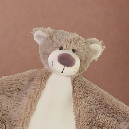 Close-up shot of the Happy Horse Bear Bella plush lovey showing the textured brown fur and cream snout against a warm brown backdrop.