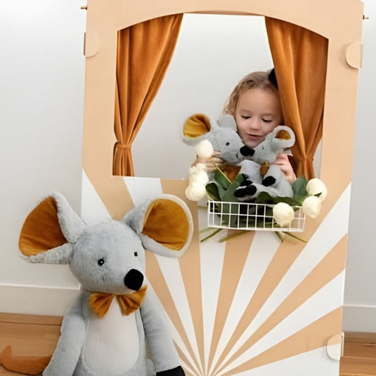 Happy Horse Mouse Misty plush toy sitting in front of a whimsical circus tent backdrop with a child playing behind it.