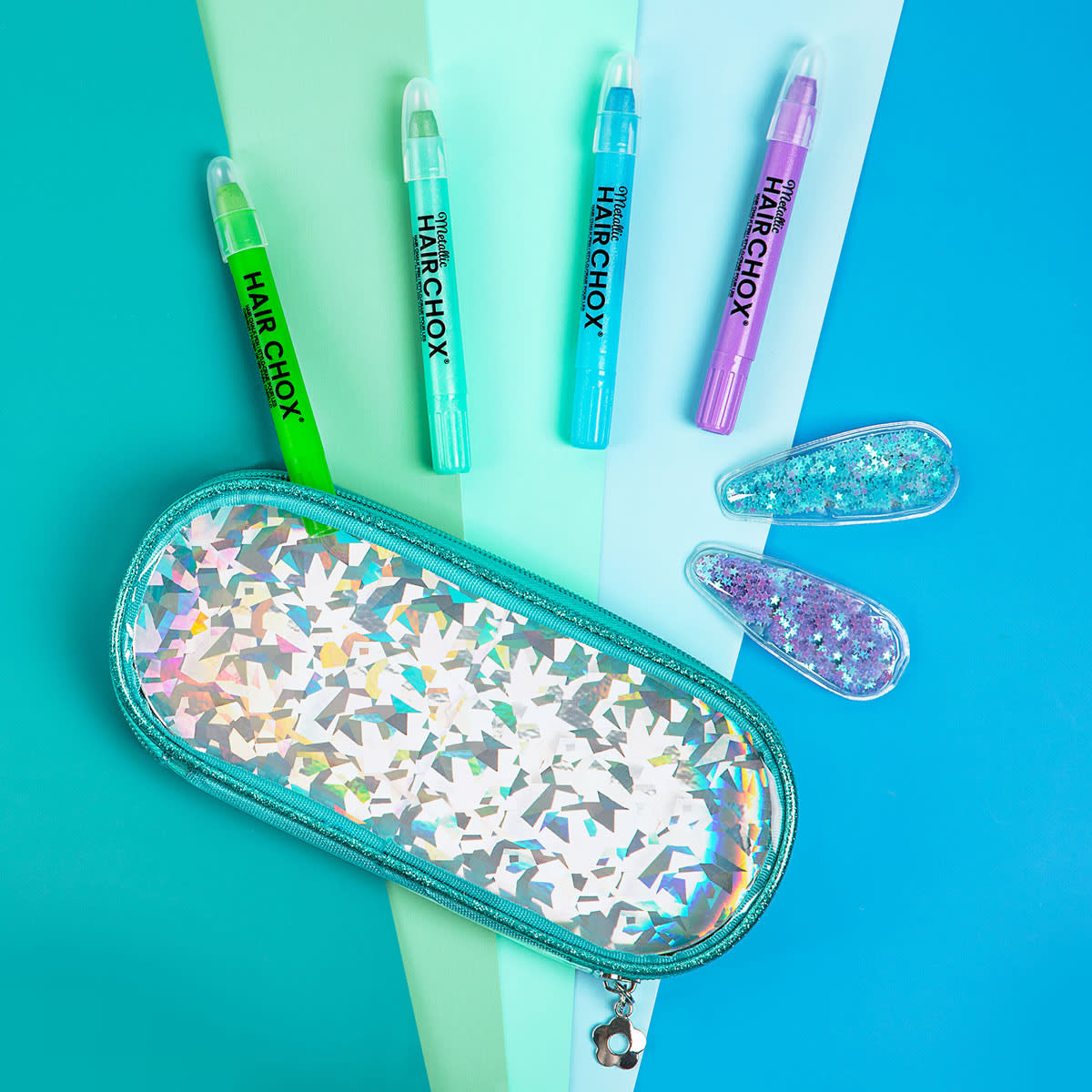Set of colorful hair chalks and a glittery case on a teal background