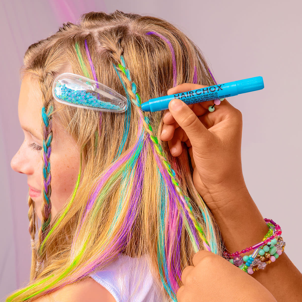 Person with colorful braided hair using a blue hair dye marker.