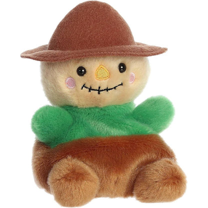 Aurora 5-inch Palm Pals Cornelius Scarecrow plush toy showing its tan face, dark brown hat, bright green shirt, brown pants, and stitched smile with an embroidered yellow nose.