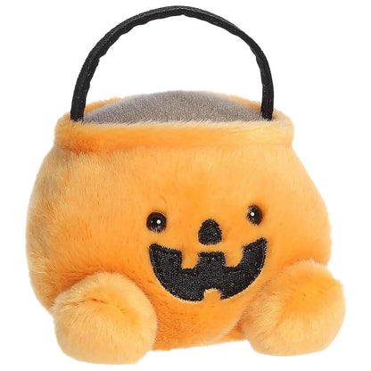 Aurora 5-inch Palm Pals Bucky Candy Bucket plush toy sitting forward showing its orange pumpkin pail body, black arched handle, and cute jack-o'-lantern face.