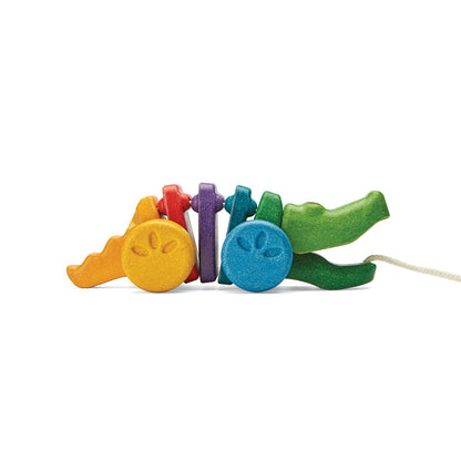 Side profile of the sustainable PlanToys wooden alligator toy showing its jointed green, blue, purple, and orange segments.