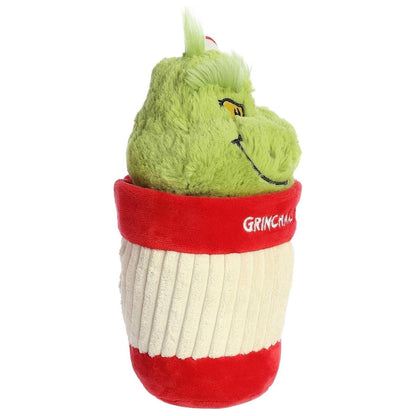 Side profile view of the Grinch holiday cup plush highlighting the ribbed texture of the cream cup and the striped straw.