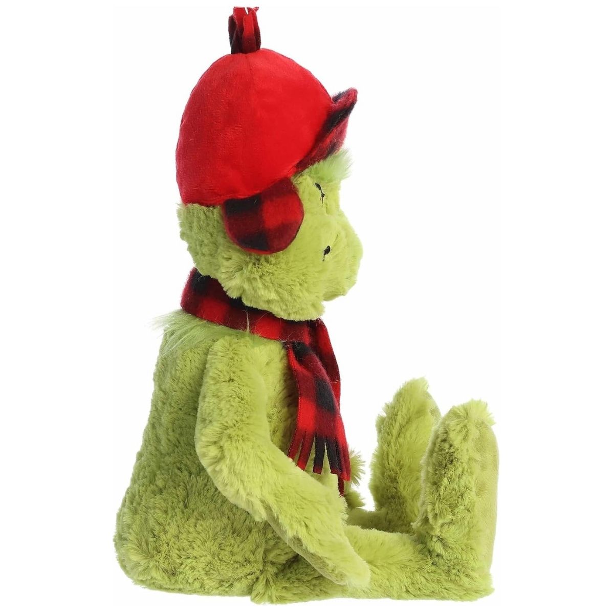A side view of the sitting 11-inch Wilderness Grinch plush highlighting his relaxed posture and the details of his plaid earflap hat.