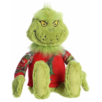 Straight front view of the sitting Grinch stuffed animal showing his classic smirk, green fur, and patterned sweater sleeves.