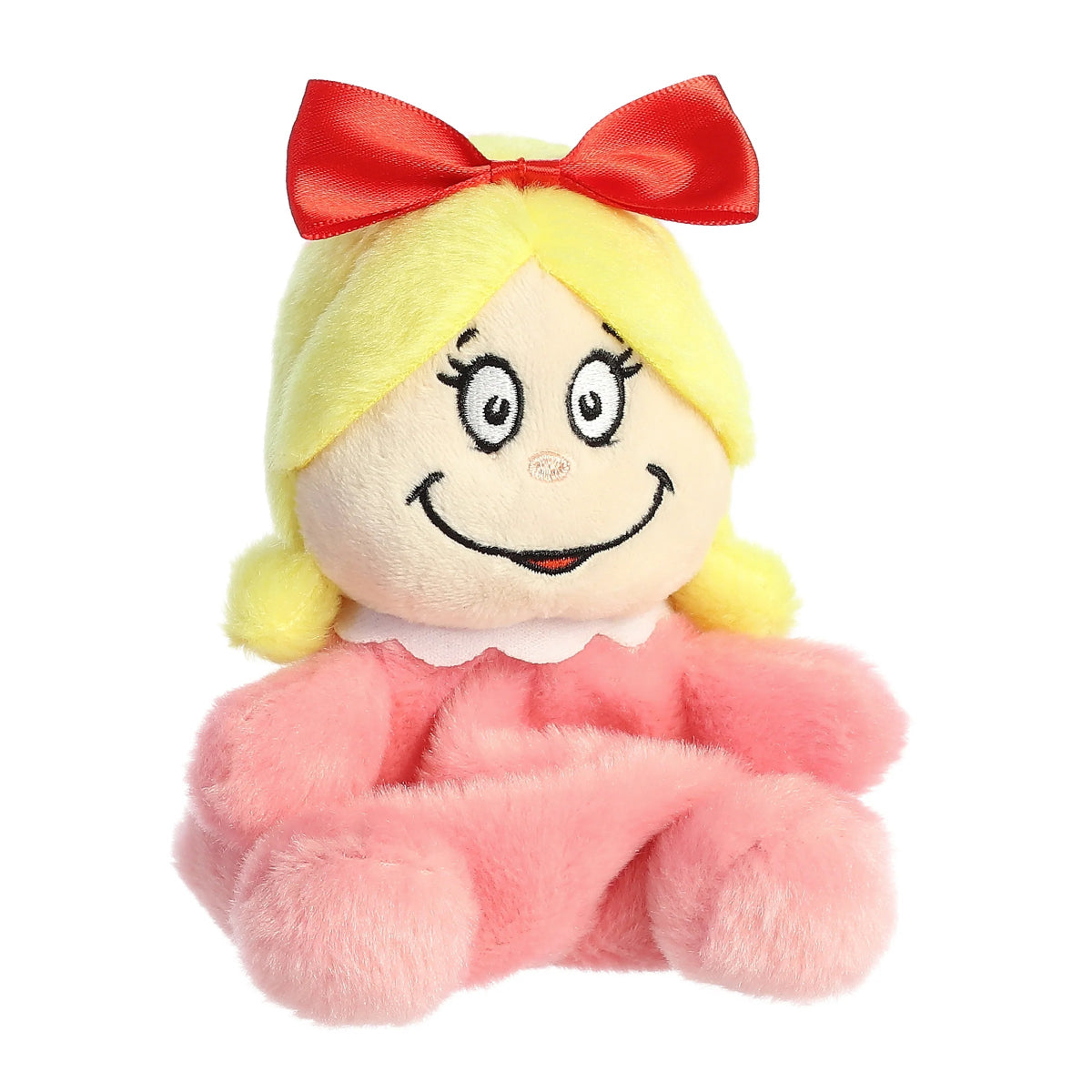 Aurora 5-inch Palm Pals Cindy-Lou Who plush toy sitting forward showing her bright yellow hair, large red bow, pink dress with a scalloped white collar, and a big stitched smile.