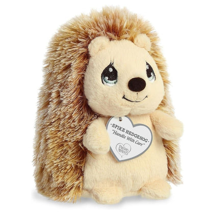 Front angled view of the 6.5-inch Aurora Precious Moments Spike Hedgehog plush toy featuring fluffy brown fur and a "Handle With Care" heart tag.