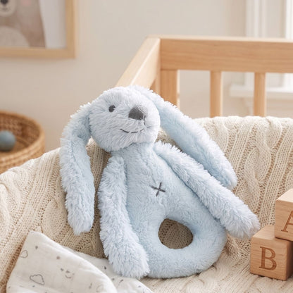 Happy Horse Rabbit Richie blue plush rattle resting on a soft blanket inside a woven nursery basket.