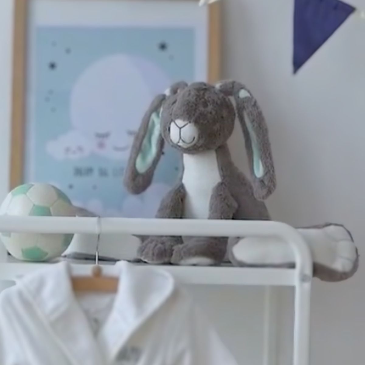 Happy Horse Rabbit Twine grey plush bunny sitting on a white modern changing table shelf in a beautifully decorated nursery.