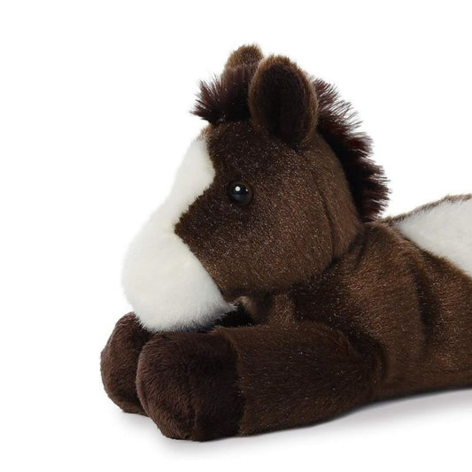 Close-up view of the pinto horse's face highlighting its dark eyes, white blaze muzzle, and dark brown ears.