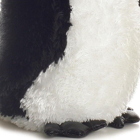 Close-up view of the soft penguin plush highlighting its fluffy white belly and black webbed feet.