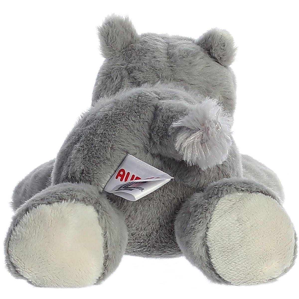 Back view of the resting rhino stuffed animal showing its grey plush body, white foot pads, and small fluffy tail.