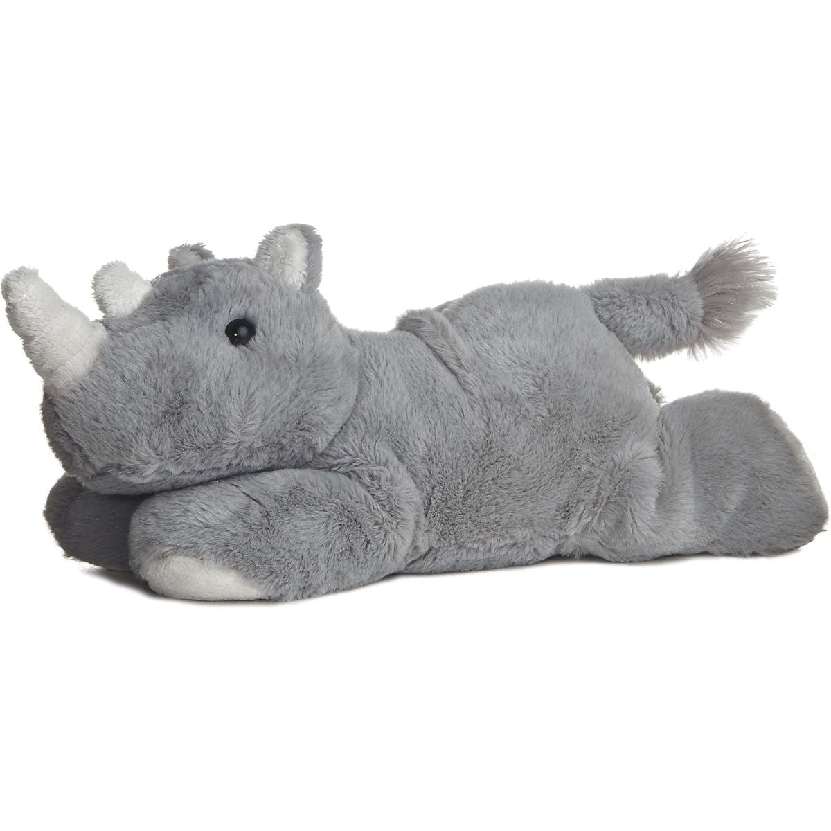 Angled side view of the Aurora Mini Flopsie Rhino 8-inch stuffed animal resting on its belly, featuring soft grey fur, two white horns, and a fluffy tail.
