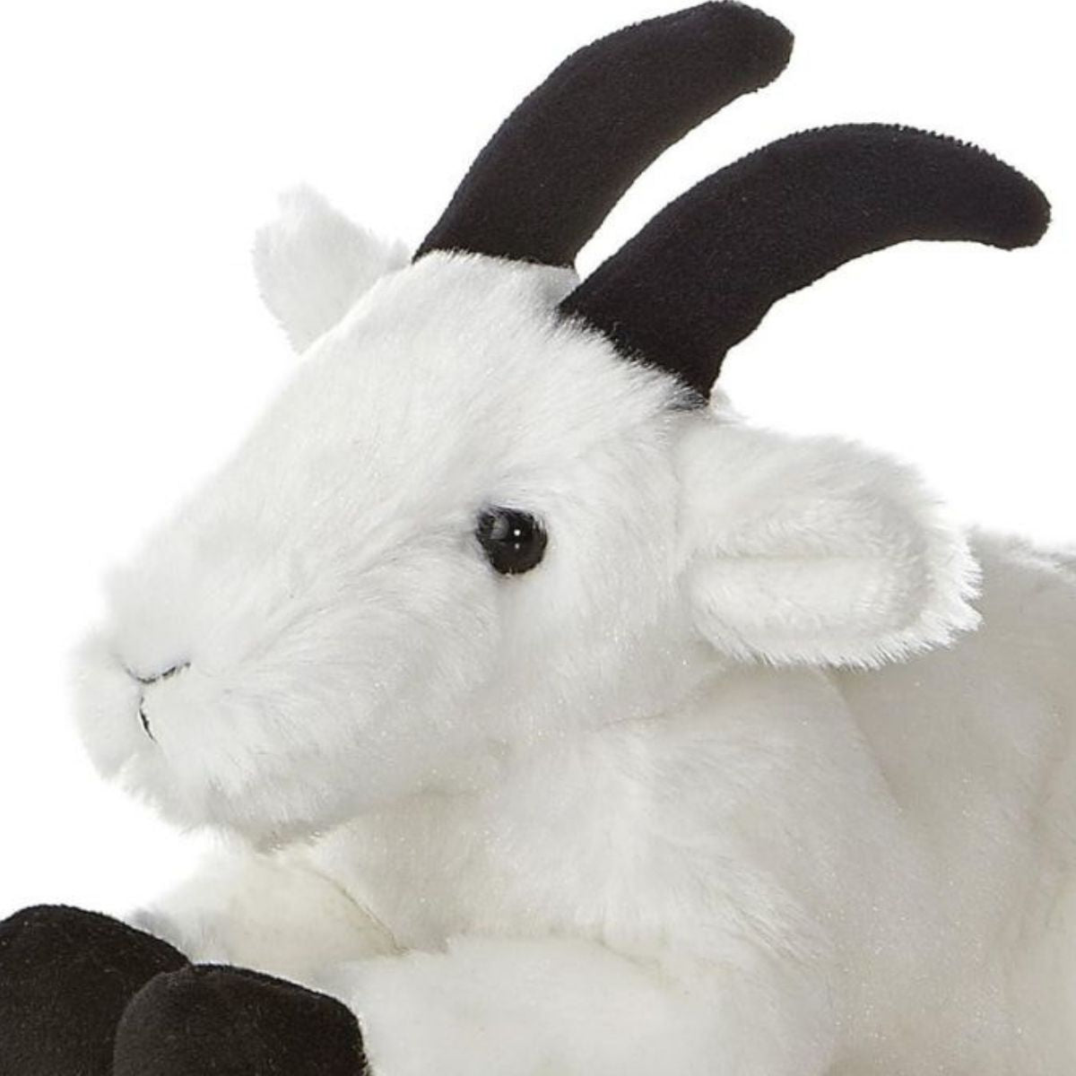 Close-up angled front view of the soft Mini Flopsie mountain goat plush showing its face, dark eyes, and black horns.