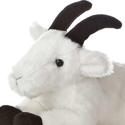 Close-up angled front view of the soft Mini Flopsie mountain goat plush showing its face, dark eyes, and black horns.