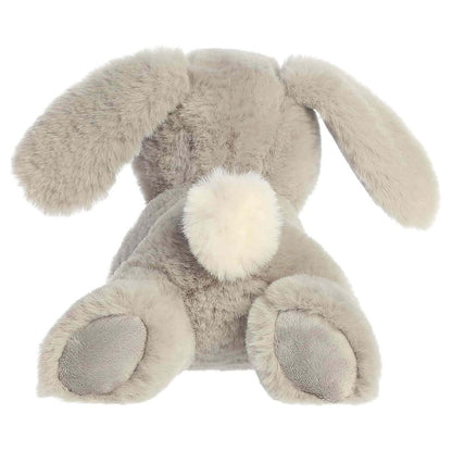 Back view of the Aurora Flopsie bunny plush toy showing its soft grey back, floppy ears resting down, grey foot pads, and a bright white cotton tail.