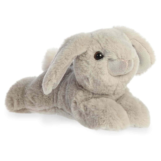 Angled view of the Aurora Flopsie 8-inch Dusty Grey Lop Bunny plush laying down, showing its soft light grey fur and long floppy ears.