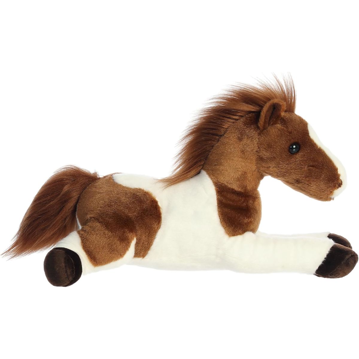 Side profile view of the cuddly Tola Pinto Horse stuffed animal resting comfortably on its tummy.