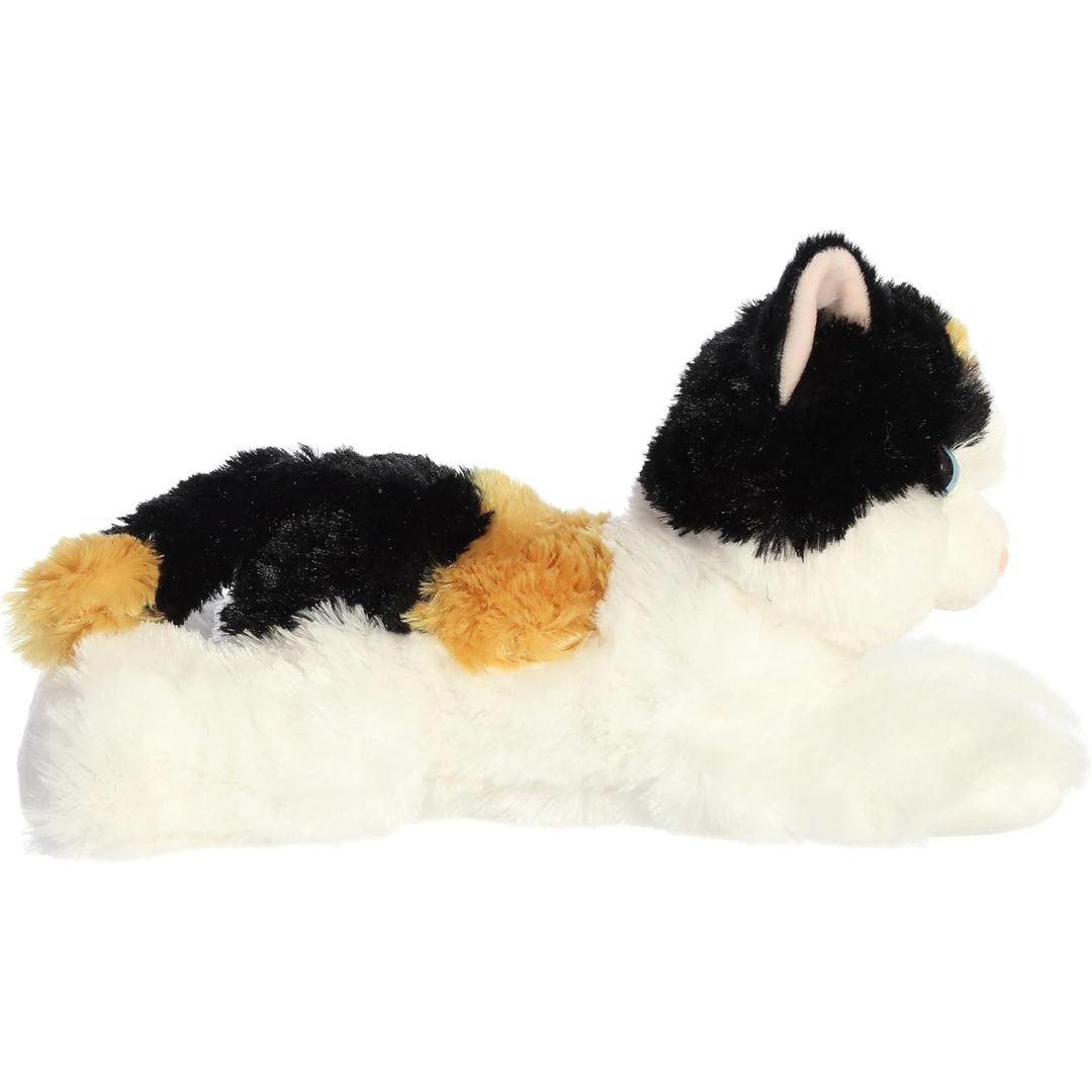 Side profile view of the calico cat plush highlighting her relaxed lying pose.