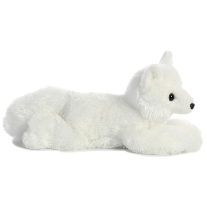 Side profile view of the white arctic fox plush showing its lounging posture, short legs, and fluffy white tail.