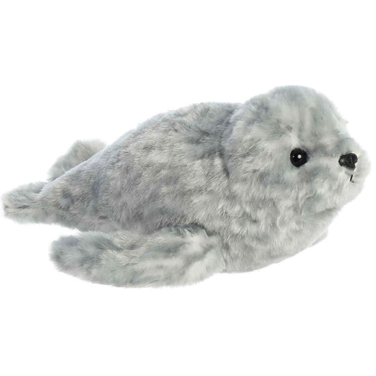Angled front view of the 8-inch Aurora Mini Flopsie Harbor Seal stuffed animal resting on its tummy, showing its mottled grey plush coat and front flippers.