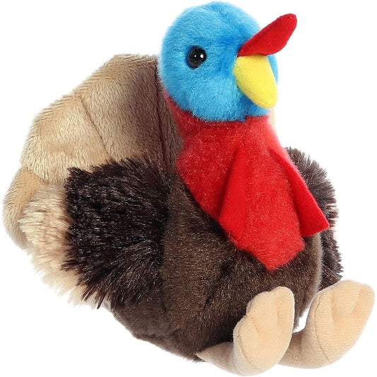 Angled front view of the Aurora Mini Flopsie Thomas Turkey 8-inch plush featuring a blue head, red wattle, dark brown body, and tan tail feathers.