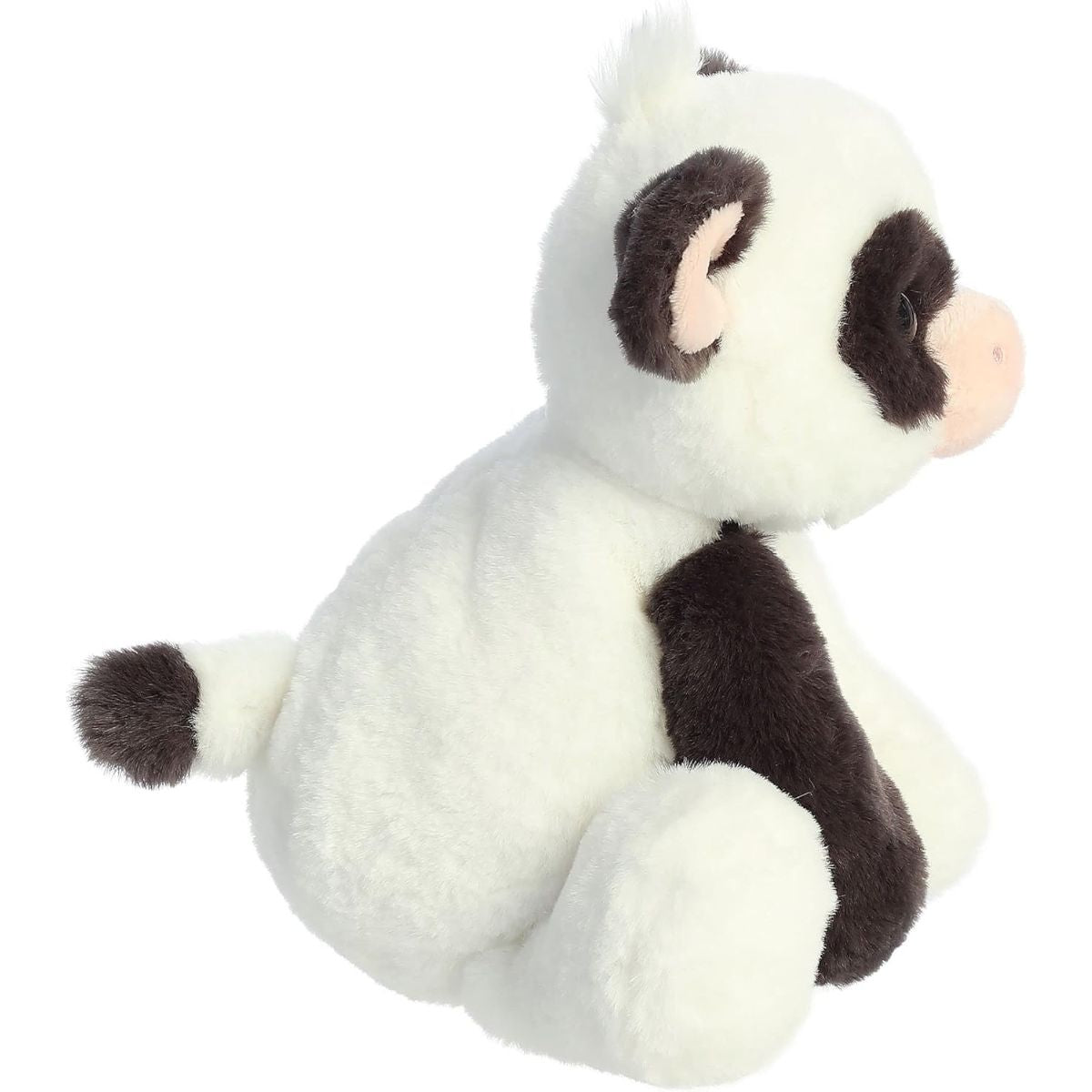 Side view of the Bessie Cow stuffed animal showing its sitting posture and soft white and black plush profile.