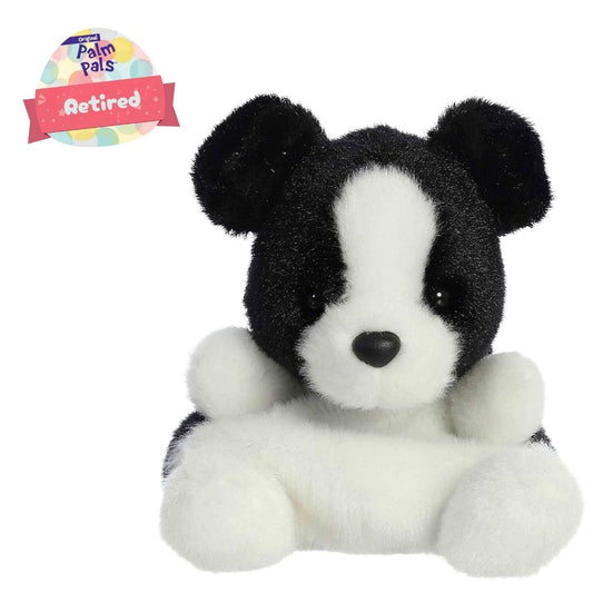 Angled view of the Aurora Palm Pals 5-inch Brody Collie plush sitting upright, showing his black and white fur, white facial blaze, and a "Retired" badge.