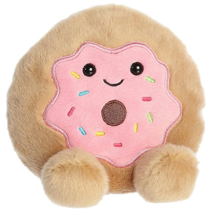 Angled front view of the soft tan Palm Pals donut plush showing its sweet smile and rosy cheeks.