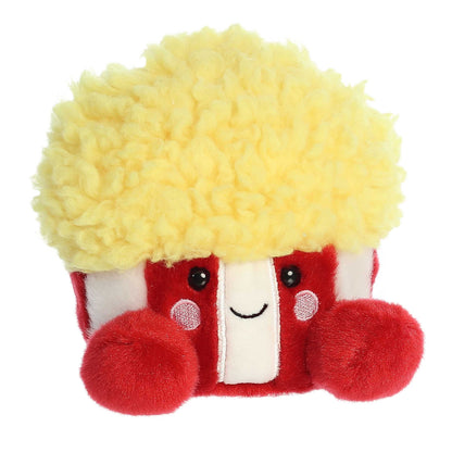 Angled view of the Aurora Palm Pals 5-inch Butters Popcorn plush sitting upright, showing its red and white striped bucket and fluffy yellow popcorn top.