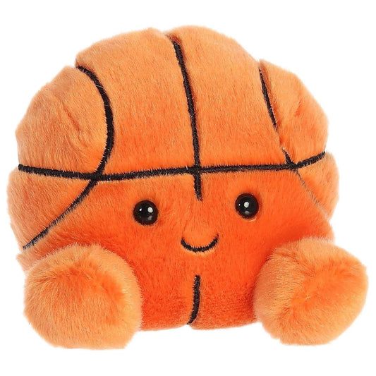 Angled view of the Aurora Palm Pals 5-inch Hoops Basketball plush sitting upright, showing its bright orange plush, black lines, and little feet.