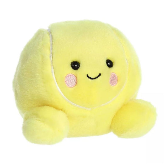 Angled view of the Aurora Palm Pals 5-inch Ace Tennis Ball plush sitting upright, showing its bright yellow plush, white curved lines, and rosy cheeks.