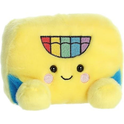 Aurora 5-inch Palm Pals Doodle Crayon Box plush toy showing its rectangular yellow body, blue side accents, embroidered rainbow crayon tip logo, and a sweet smiling face with blushing cheeks.