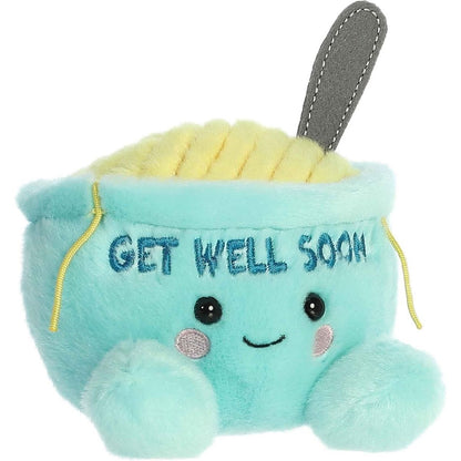 Aurora 5-inch Palm Pals Get Well Soon Welly Chicken Soup plush toy showing its mint-green bowl body embroidered with "GET WELL SOON", yellow plush noodles, a gray fabric spoon, and a sweet smiling face.