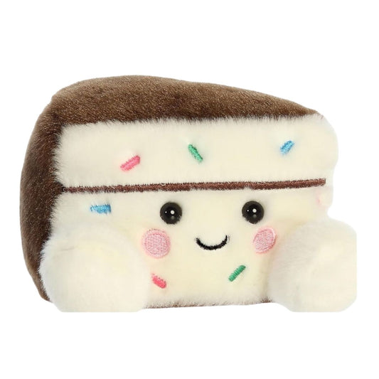 Angled front view of the soft Palm Pals cake slice plush sitting upright with white frosting and a brown back.