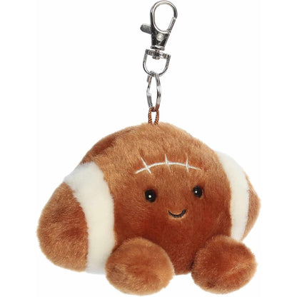 Angled front view of the soft brown Palm Pals football plush showing its white stripes and metal clip.