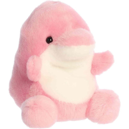 Angled view of the Aurora Palm Pals 5-inch Amazonia Pink Dolphin plush sitting upright, showing its bright pink body, white belly, and rounded snout.