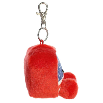Side profile view of the Palm Pals American flag plush highlighting its squishy body, red plush back, and metal clip attachment.