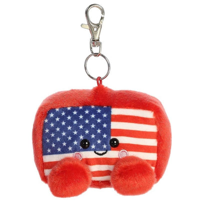 Front view of the Aurora Palm Pals 4-inch Indivisible Flag clip-on plush, featuring an American flag design, sweet face, red feet, and a metal keychain clip.