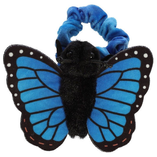 Top-down view of the bright blue and black butterfly resting flat against its blue scrunchie-style wristband.