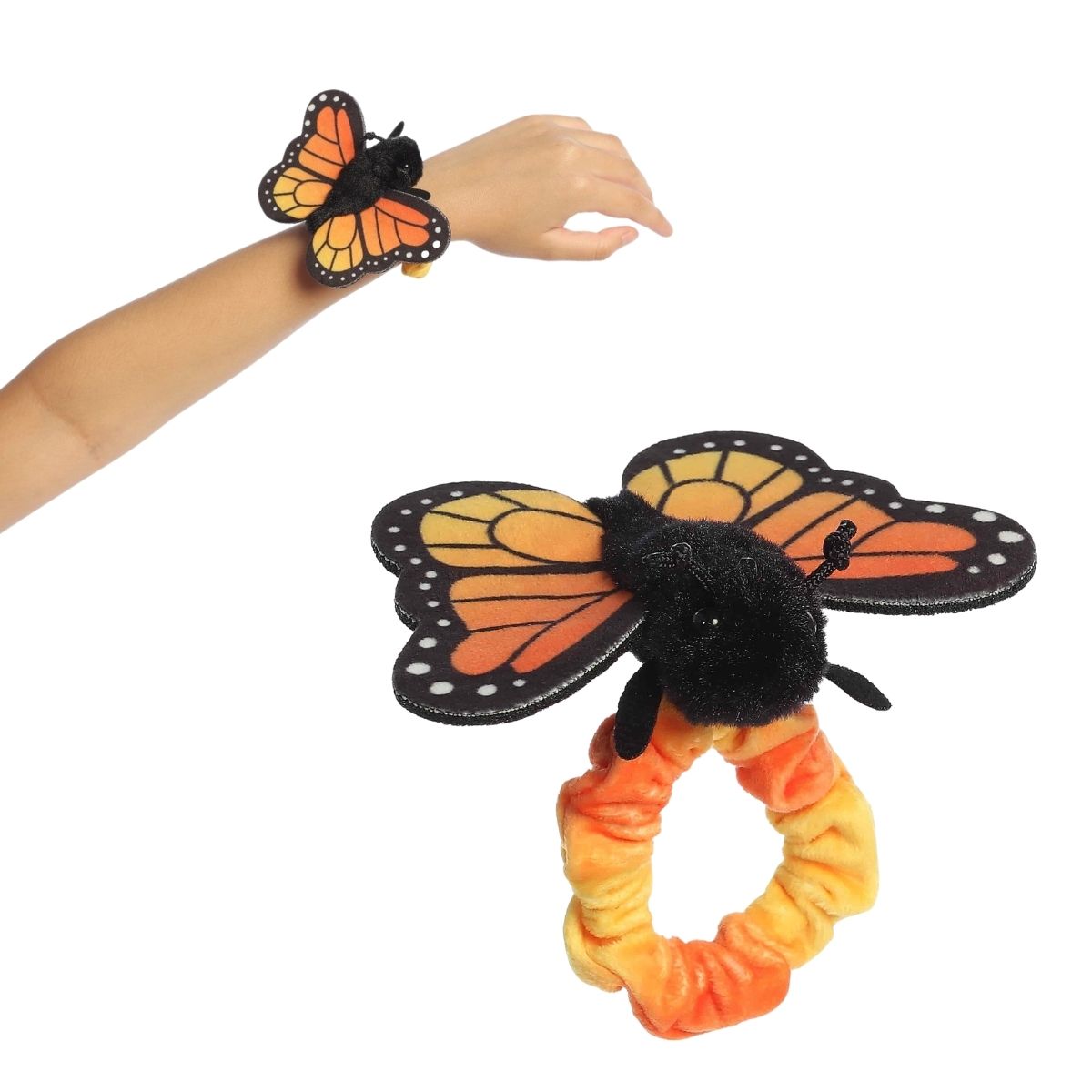 A person's arm wearing the 5-inch Aurora Wrist Flingers Monarch Butterfly plush with a close-up of the classic orange and black butterfly toy.